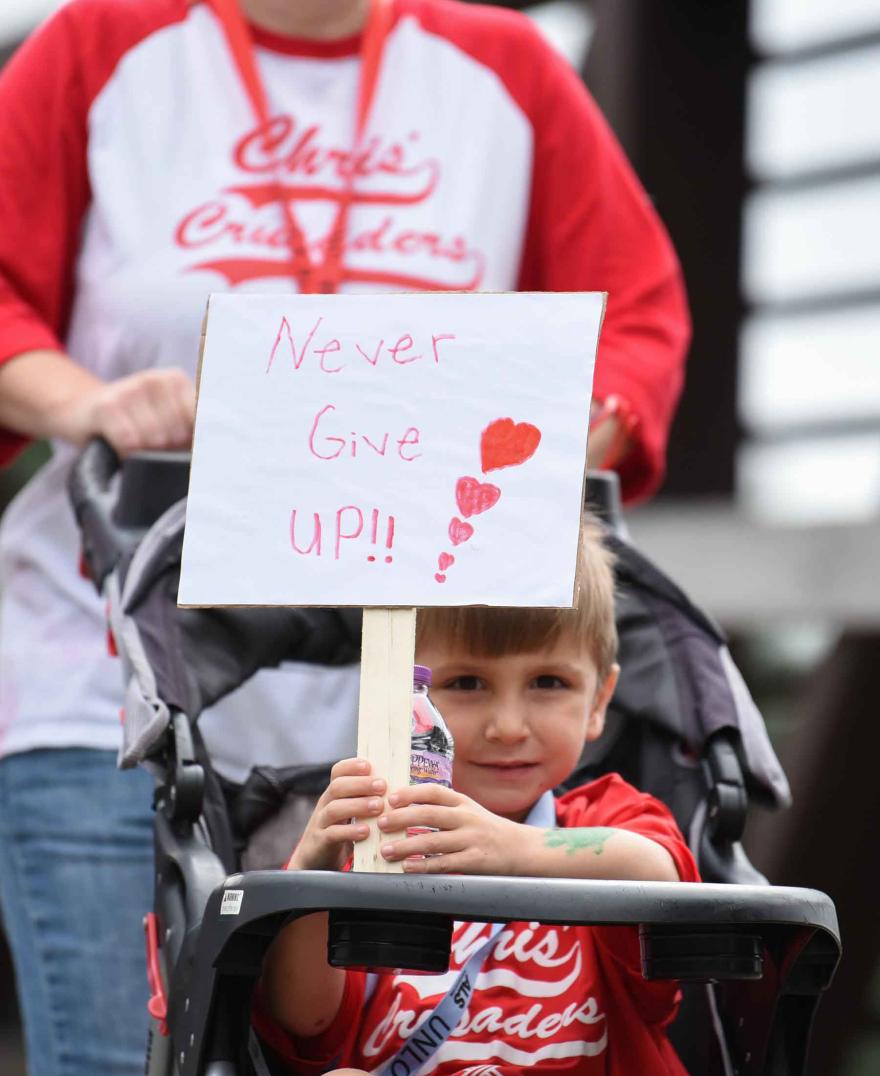 Child with a Never Give Up sign at a Walk to Defeat event
