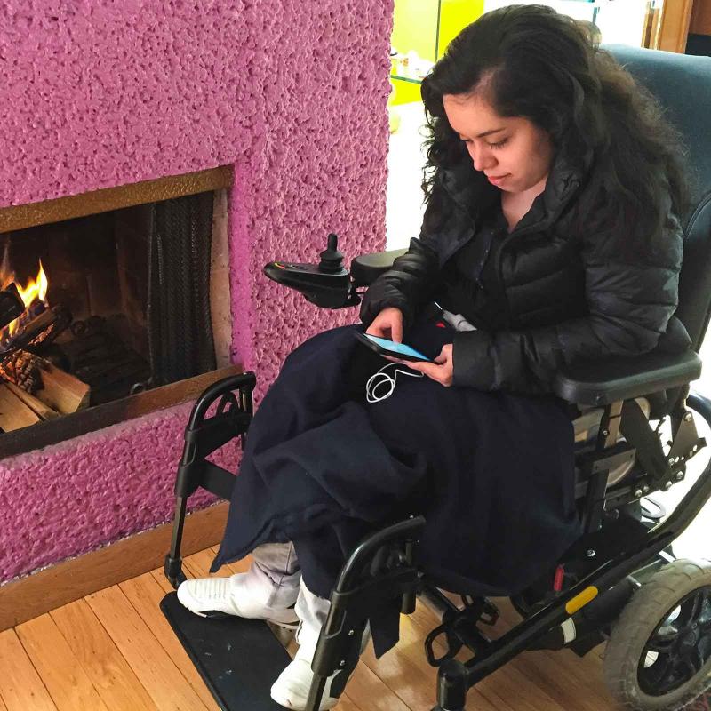 A young woman in a wheelchair looking at her mobile phone
